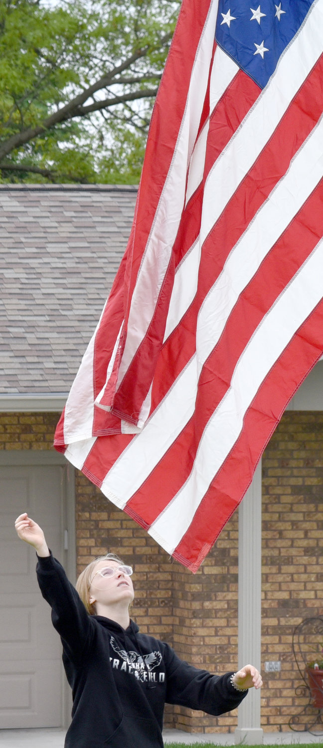 Mara Jones helps raise a flag at Sharon Hill Cemetery.